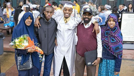 一位身穿白色礼服的BC毕业生在毕业典礼前与家人或朋友合影